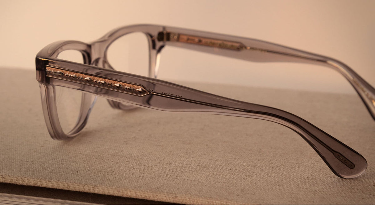 Close-up of a grey Oliver Peoples acetate temple with an inlaid metal filigree