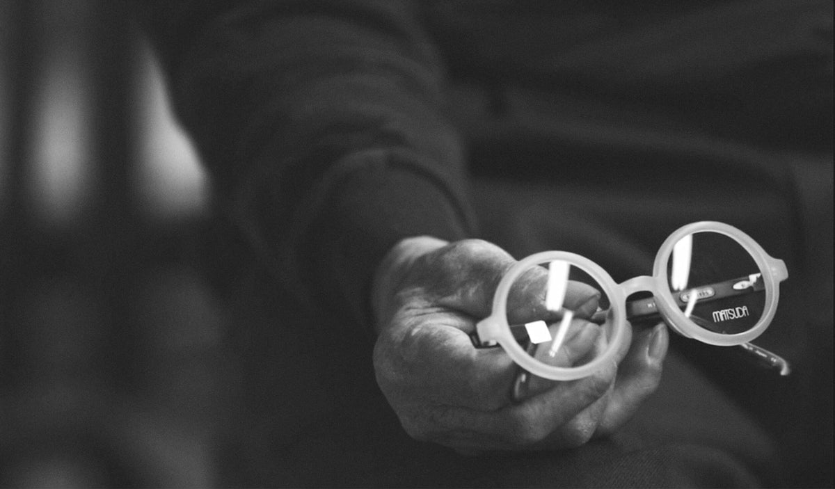 Craftsman's hand holding a round Matsuda frame, black and white